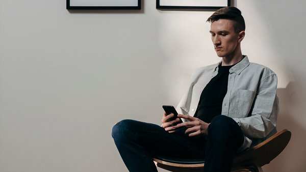 Man kijkt angstig naar zijn mobiele telefoon – prijsstijgingen Man kijkt angstig naar zijn mobiele telefoon – prijsstijgingen