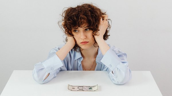 Une femme fait la moue devant un billet de banque – économiser de l’électricité