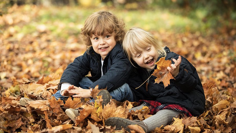 Twee kinderen zitten in herfstbladeren