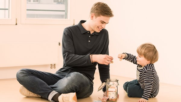 Kindje en jonge man sparen geld in een spaarpot Kindje en jonge man sparen geld in een spaarpot