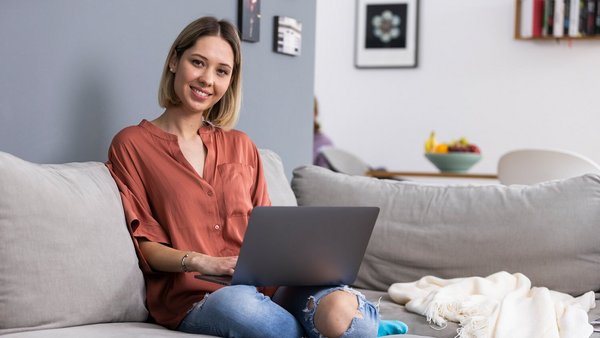 Vrouw thuis aan het werk met laptop op de zetel
