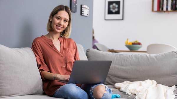 Une femme qui travaille depuis son domicile avec un ordinateur portable sur le canapé