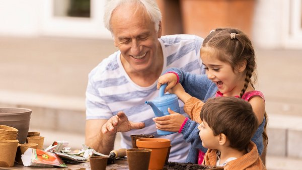 Un grand-père et des petits-enfants plantent des fleurs Un grand-père et des petits-enfants plantent des fleurs