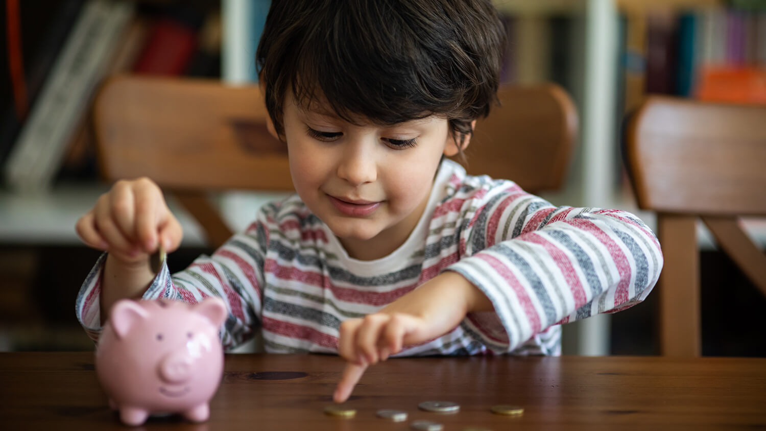 Un enfant avec une tirelire et des pièces de monnaie – frais fixes mensuels dans le foyer Un enfant avec une tirelire et des pièces de monnaie – frais fixes mensuels dans le foyer